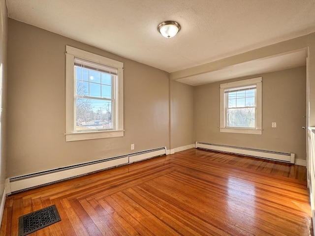 spare room featuring baseboard heating and hardwood / wood-style flooring