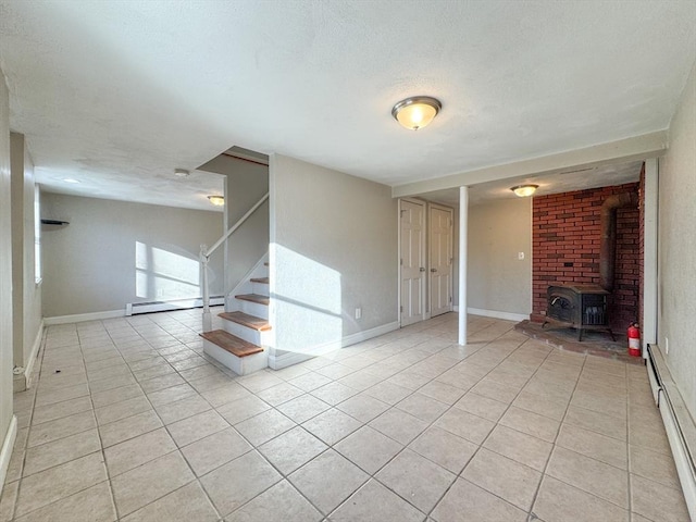 unfurnished living room with light tile patterned floors, a wood stove, and baseboard heating