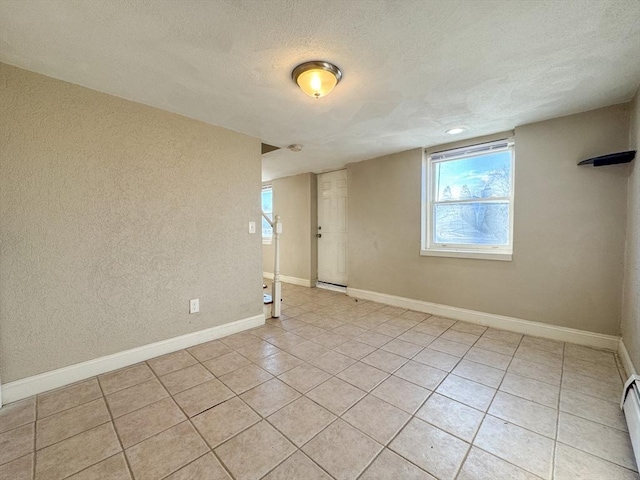 tiled empty room with a baseboard radiator and a textured ceiling