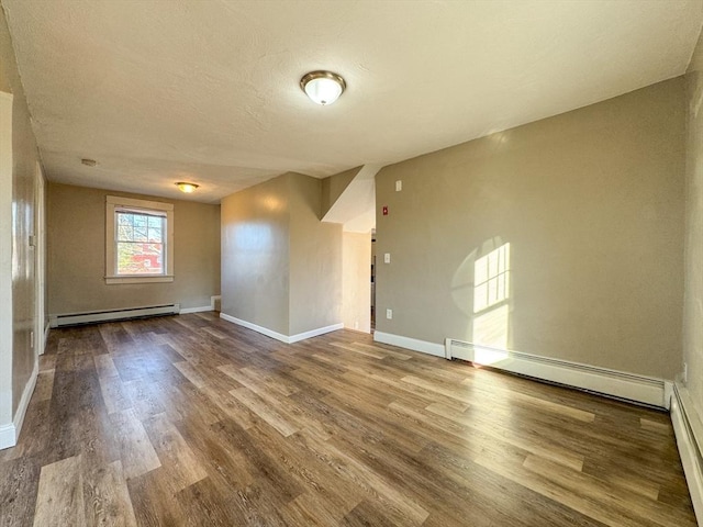 empty room with a baseboard radiator, hardwood / wood-style floors, and a textured ceiling