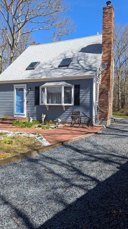 92 Santuit Pond Rd, Mashpee, MA 02649 - view of front facade with a chimney, roof with shingles, and a patio