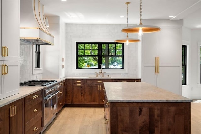 61 Westbourne Rd, Newton, MA 02459 - kitchen featuring range with two ovens, a sink, premium range hood, light wood-style flooring, and a kitchen island