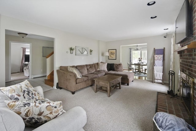 carpeted living area featuring a fireplace, stairs, a chandelier, and baseboards
