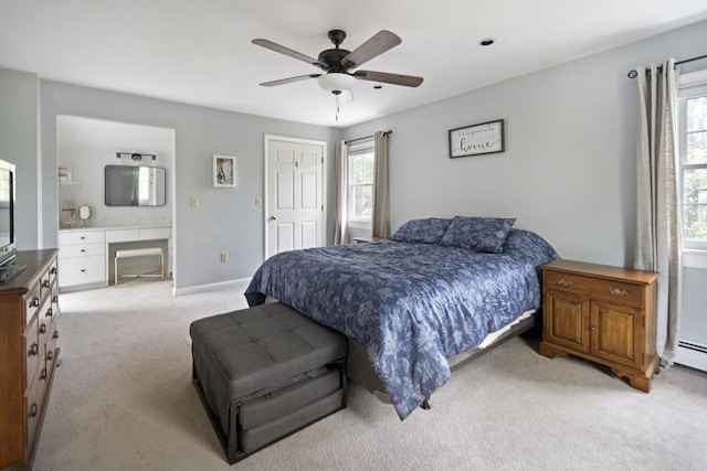 bedroom with light colored carpet, ceiling fan, ensuite bathroom, and baseboards
