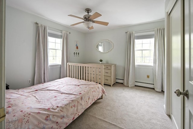 bedroom with multiple windows, light carpet, and baseboard heating