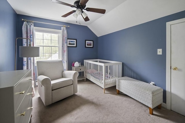carpeted bedroom with vaulted ceiling, a ceiling fan, and a nursery area