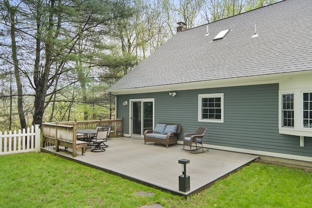 back of property with a chimney, roof with shingles, and a wooden deck