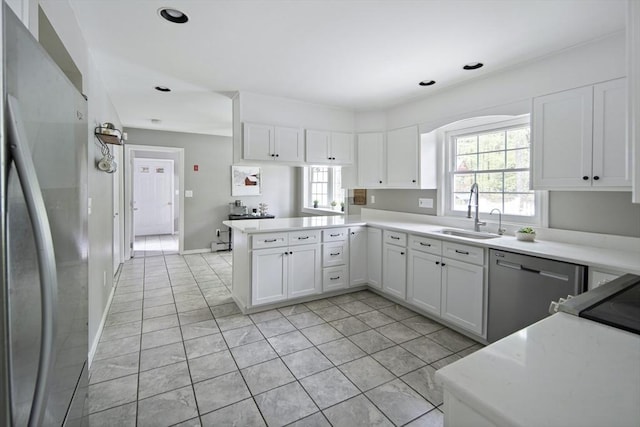 kitchen with stainless steel appliances, a sink, light tile patterned floors, a peninsula, and white cabinets