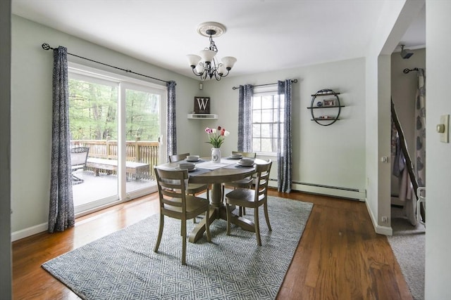 dining room featuring a chandelier, a baseboard radiator, baseboards, and wood finished floors