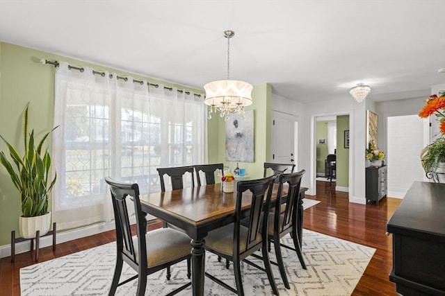 dining space with dark hardwood / wood-style flooring, a wealth of natural light, and an inviting chandelier