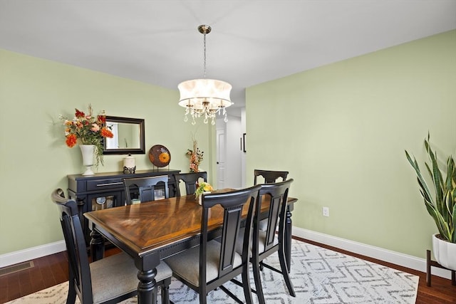 dining area with wood-type flooring and an inviting chandelier