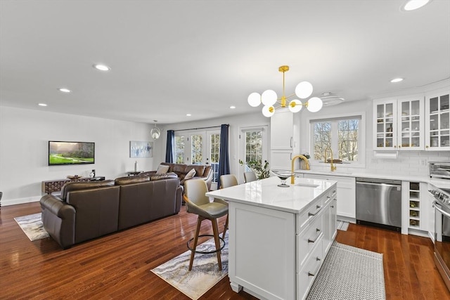 kitchen with decorative light fixtures, a center island, white cabinetry, stainless steel appliances, and dark hardwood / wood-style flooring