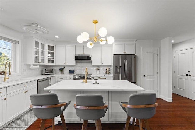 kitchen with decorative light fixtures, tasteful backsplash, sink, white cabinetry, and stainless steel appliances