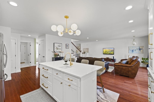 kitchen with decorative light fixtures, sink, white cabinetry, an island with sink, and dark hardwood / wood-style flooring