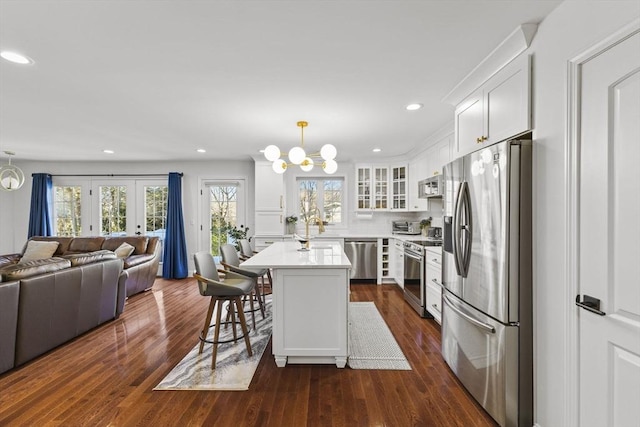 kitchen featuring a center island, a breakfast bar, hanging light fixtures, appliances with stainless steel finishes, and white cabinets