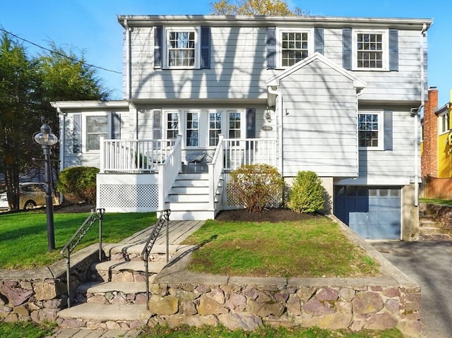 view of front of home featuring a deck, an attached garage, driveway, and a front yard