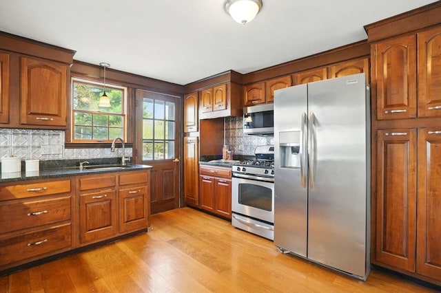 kitchen featuring brown cabinets, stainless steel appliances, decorative backsplash, and a sink