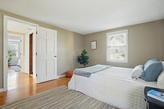 bedroom featuring baseboard heating, baseboards, and wood finished floors