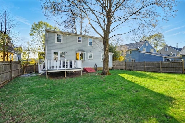 rear view of property featuring a lawn, a deck, and a fenced backyard
