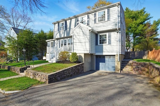 colonial house with stairway, an attached garage, fence, and aphalt driveway
