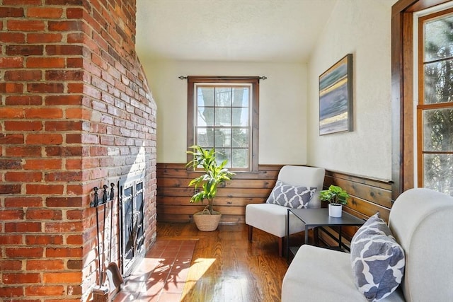 sitting room with a wainscoted wall, a fireplace, hardwood / wood-style flooring, and wood walls
