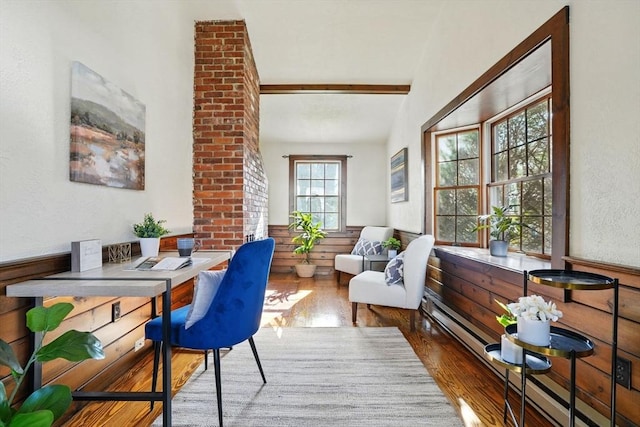 interior space with beamed ceiling, wainscoting, wood finished floors, and a baseboard radiator