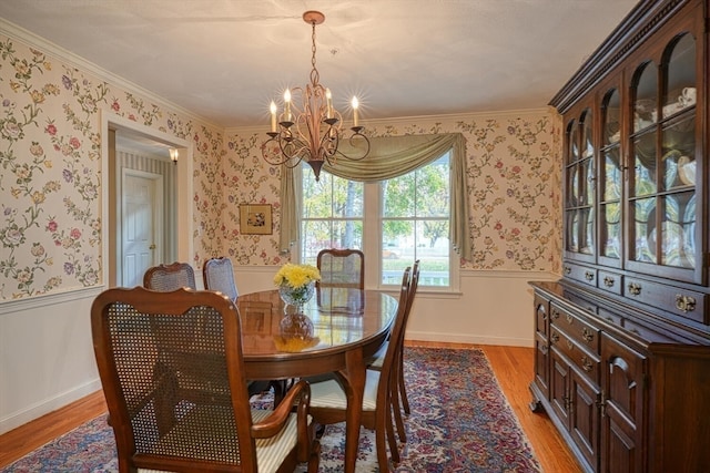 dining space featuring crown molding, light wood-type flooring, and an inviting chandelier