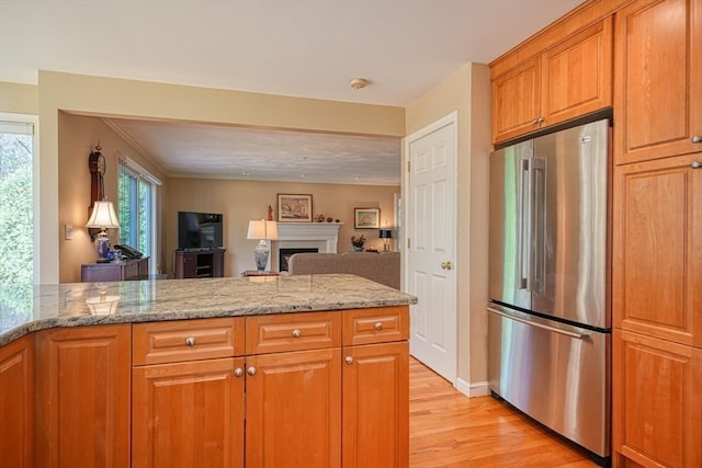 kitchen with light hardwood / wood-style floors, stainless steel refrigerator, and light stone counters