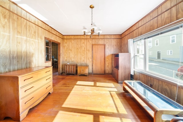 miscellaneous room with hardwood / wood-style flooring, a chandelier, and wooden walls