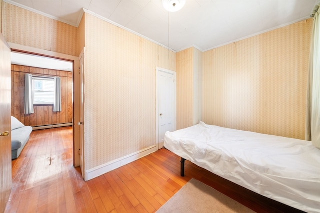 bedroom featuring ornamental molding, hardwood / wood-style floors, and a baseboard radiator