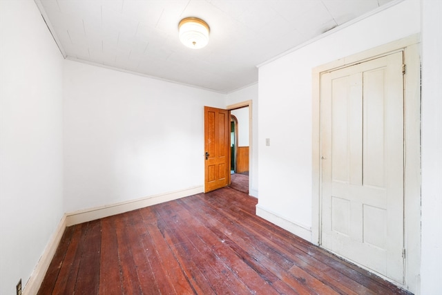 unfurnished bedroom featuring dark hardwood / wood-style flooring, a closet, and ornamental molding