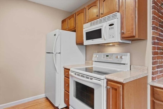 42 Phillips Rd Unit 1, Holden, MA 01520 - kitchen featuring white appliances, brown cabinets, light countertops, light wood-style flooring, and baseboards
