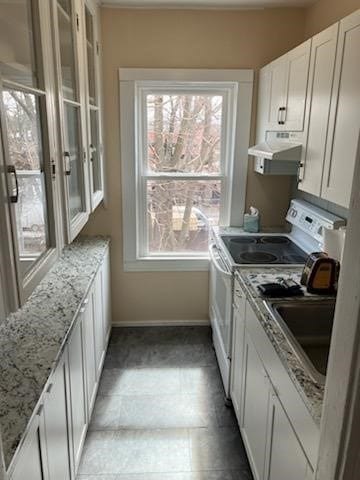 kitchen featuring light stone countertops, sink, white cabinets, and white stove