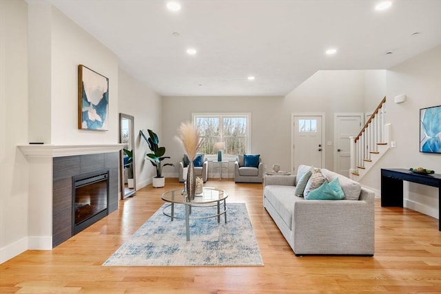 living room featuring a tiled fireplace and light hardwood / wood-style floors