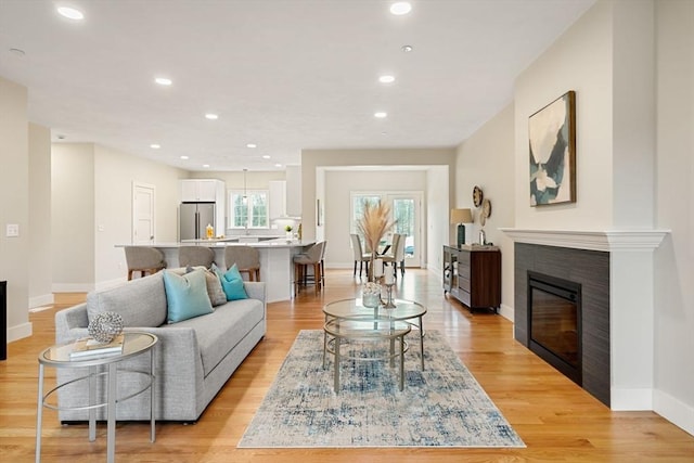 living room with a tile fireplace and light wood-type flooring