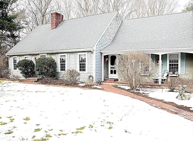 cape cod home with a shingled roof and a chimney