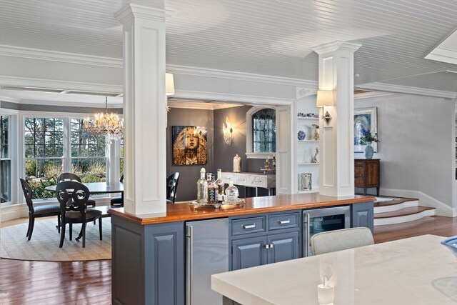 bar featuring wooden counters, beverage cooler, ornamental molding, dark hardwood / wood-style floors, and an inviting chandelier