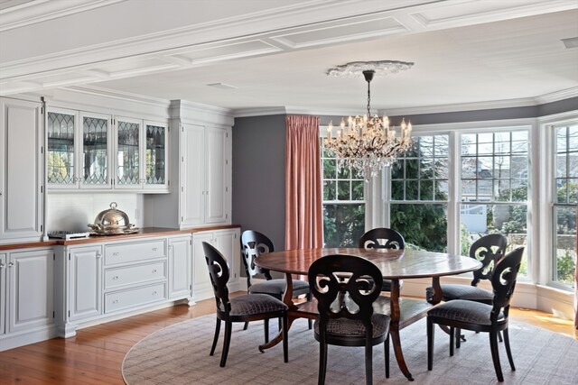 dining room with a notable chandelier, crown molding, and light hardwood / wood-style floors