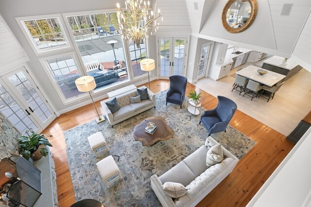 living room featuring high vaulted ceiling, a chandelier, and light wood-type flooring