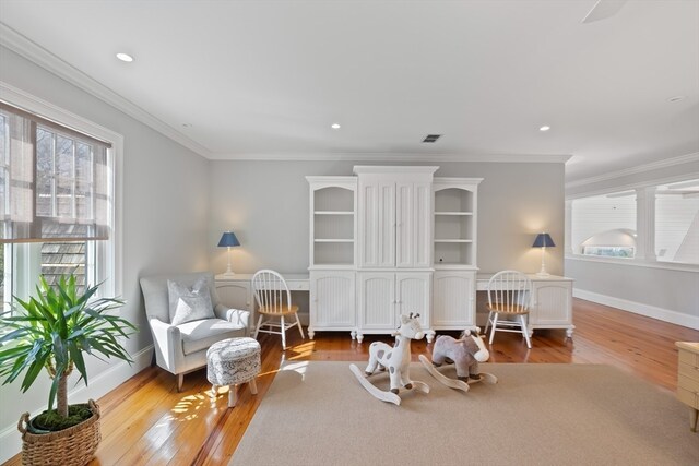 sitting room featuring ornamental molding and light wood-type flooring