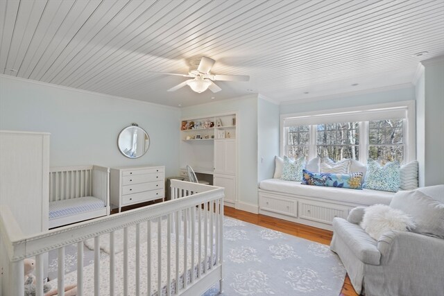 bedroom with a crib, wood ceiling, ceiling fan, and light hardwood / wood-style flooring