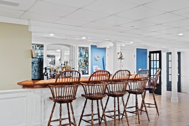 bar featuring decorative columns and light wood-type flooring