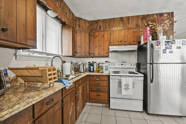 10 Gleason Rd, Shrewsbury, MA 01545 - kitchen with freestanding refrigerator, white range with electric cooktop, under cabinet range hood, light tile patterned floors, and brown cabinetry