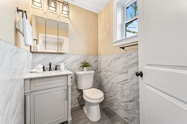 bathroom with tile patterned floors, vanity, tile walls, and toilet