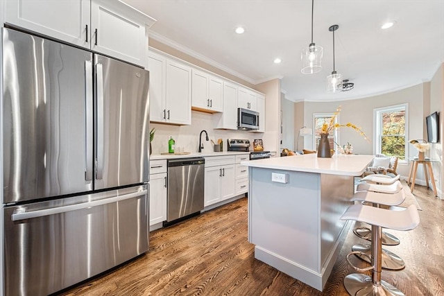 kitchen featuring pendant lighting, a center island, stainless steel appliances, and white cabinetry