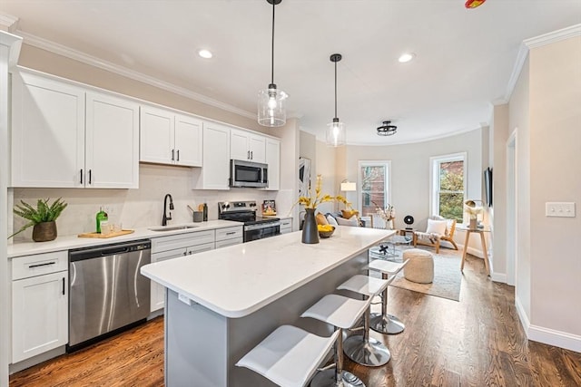 kitchen featuring appliances with stainless steel finishes, sink, a center island, white cabinetry, and a breakfast bar area