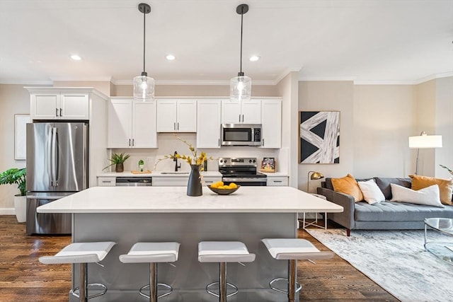 kitchen featuring a kitchen bar, appliances with stainless steel finishes, dark hardwood / wood-style flooring, decorative light fixtures, and white cabinetry