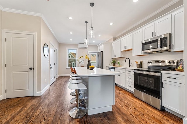 kitchen with dark wood-type flooring, hanging light fixtures, stainless steel appliances, a kitchen island, and white cabinets