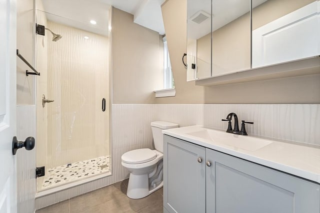 bathroom featuring tile patterned flooring, vanity, toilet, and a shower with shower door