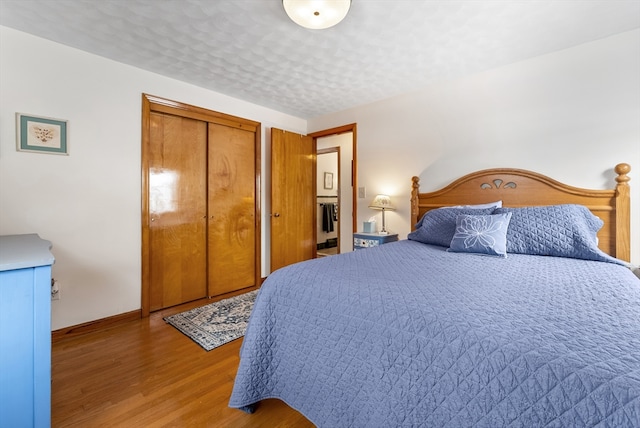 bedroom with a textured ceiling, a closet, baseboards, and wood finished floors